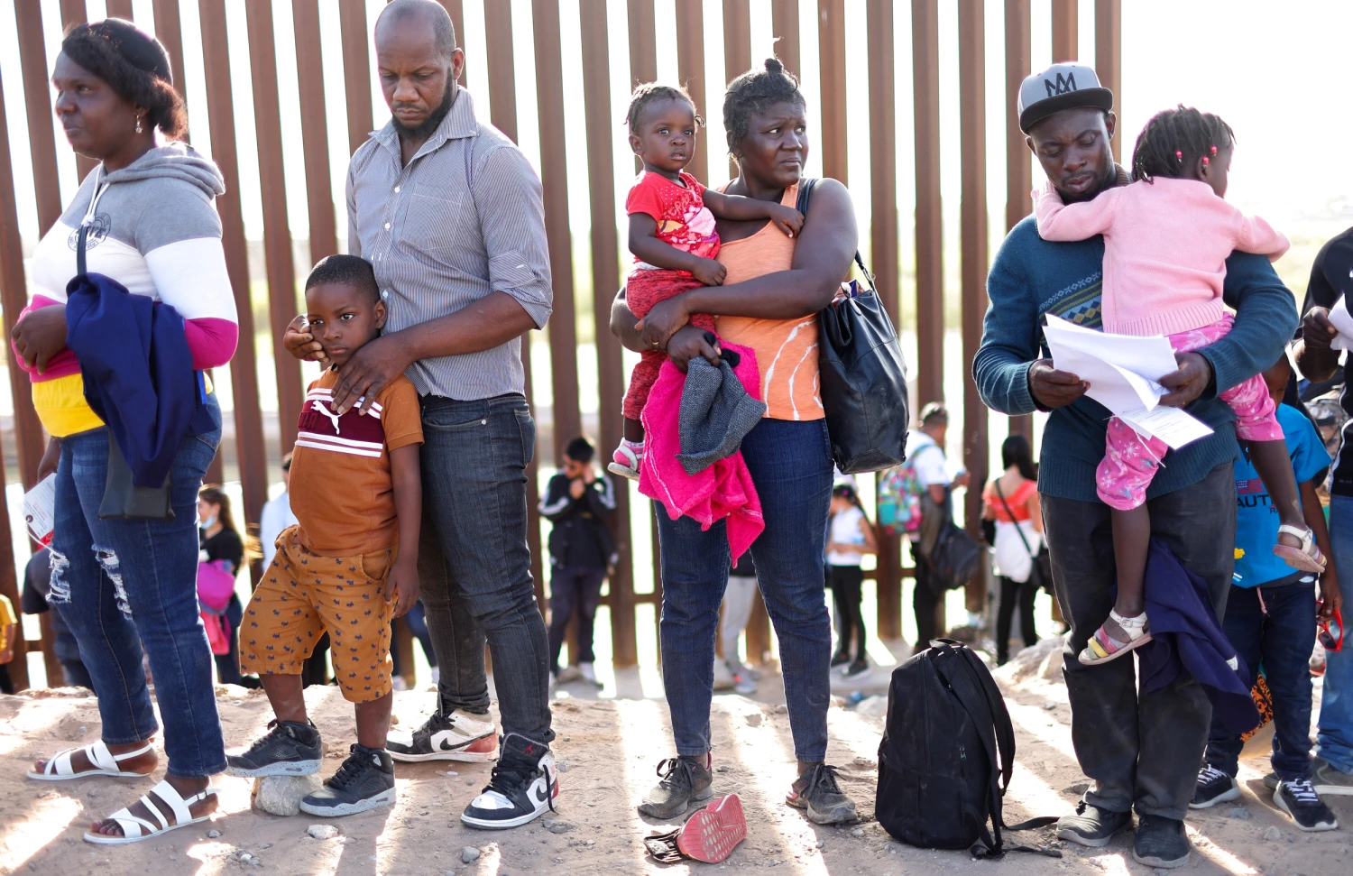 Haitian families with children waiting at the U.S. border holding documents